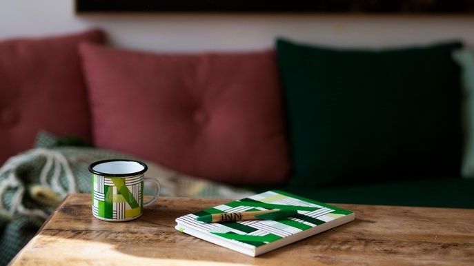 Book and coffee cup on a table in INN University colours.