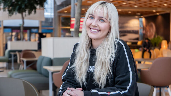 Portrett av Hannah Nordanger som sitter ved et bord i et kantinemiljø. Hun er skarp, mens miljøet er uskarpt. 