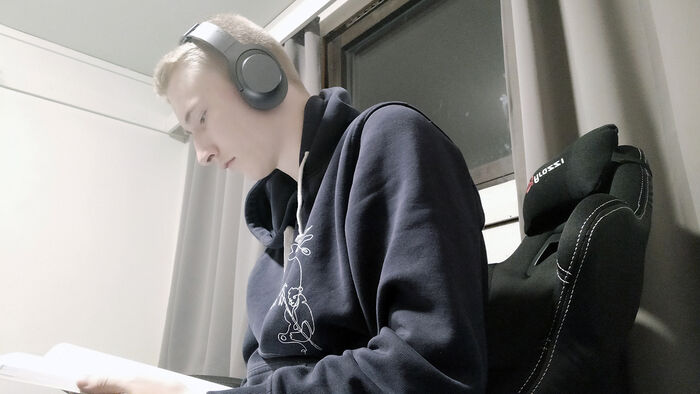 Mann med høretelefoner som leser en bok. 