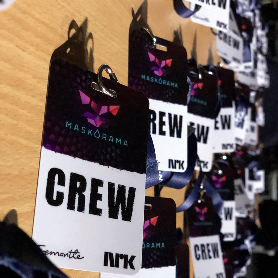 Adgangskort for crew-medlemmer av Maskorama liggende på en lys benk. 