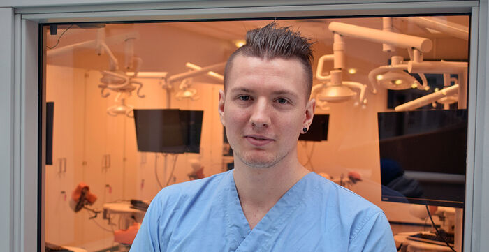 Mannlig tannpleiestudent foran øvingslabben. 