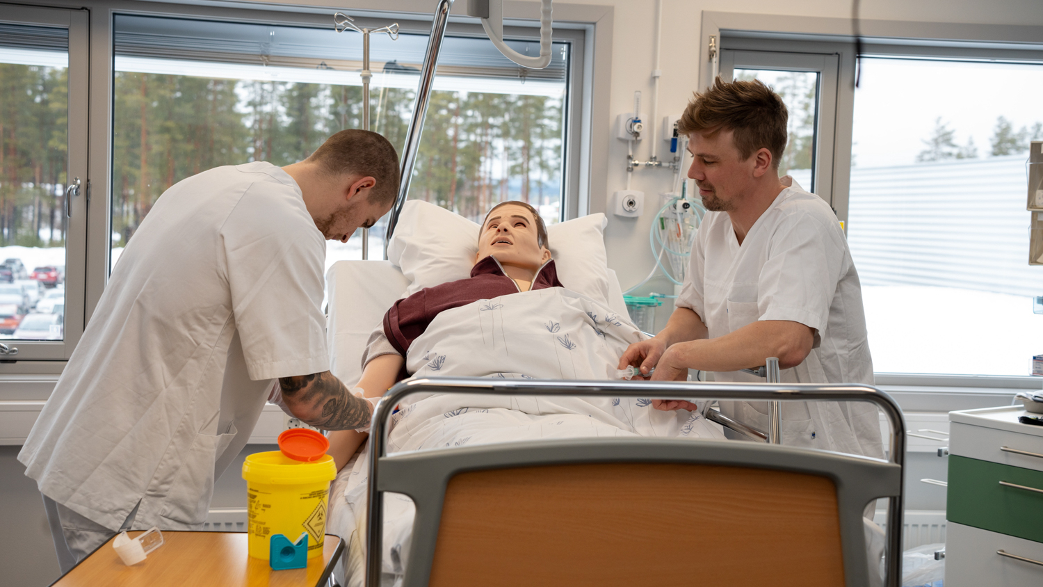 To manlige sykepleiestudenter står over patientdukken Jørgen.