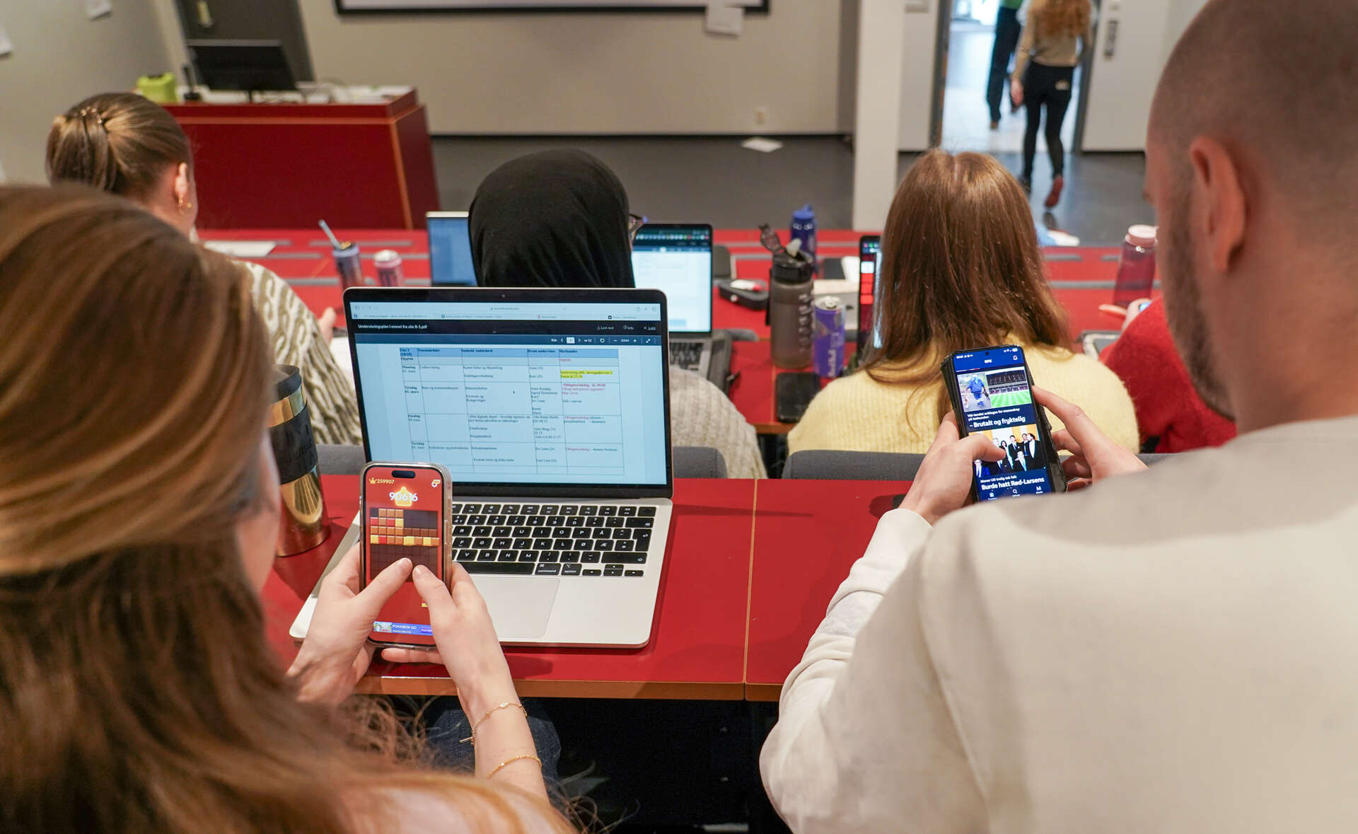 To studenter ser på mobilen sin i ei pause mellom to forelesninger i et auditorium