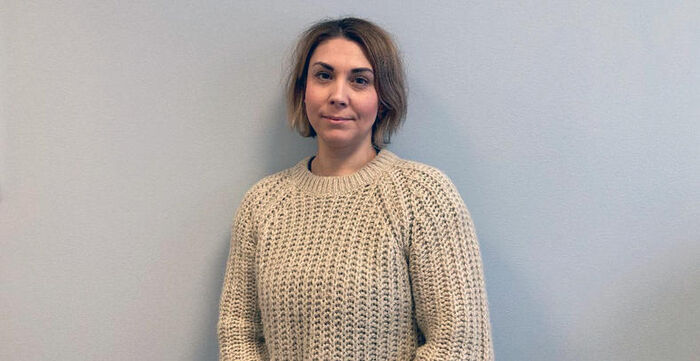 Bilde av Elin Henjesand Kvam foran en grå vegg