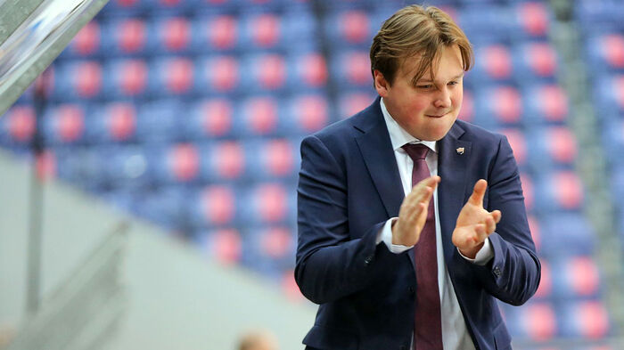 Ishockeytrener Isaac Palmgren iført mørk dress på spillerbenken i Håkons Hall. 