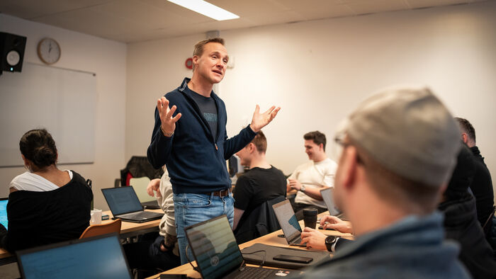 Tormod Heier står midt i et klasserom med studenter og prater