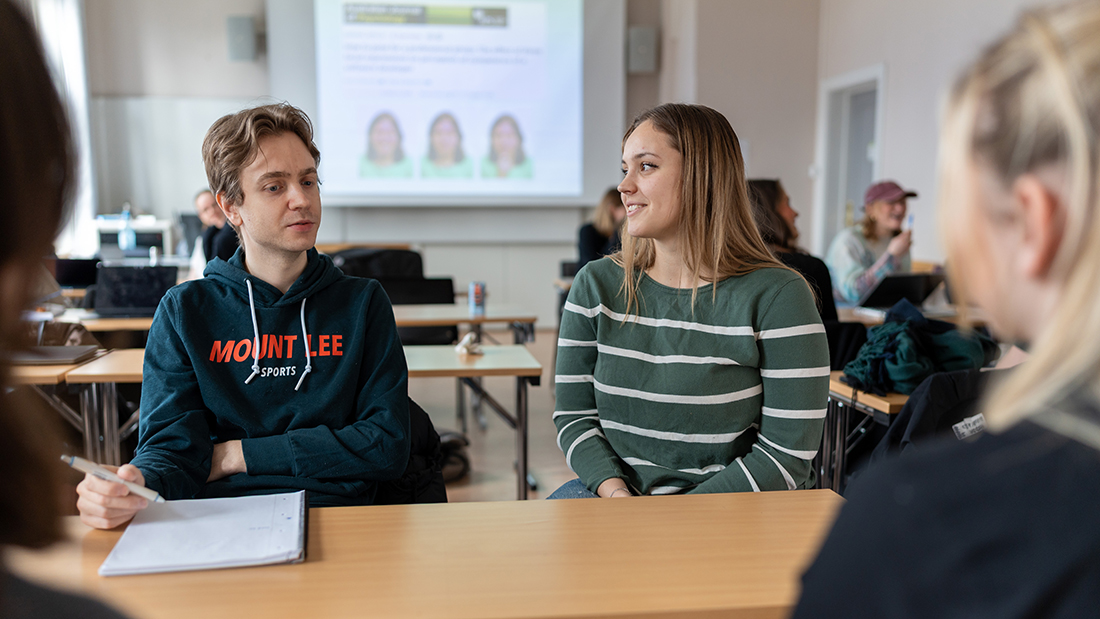Studenter som sitter rundt et bord og skravler. 