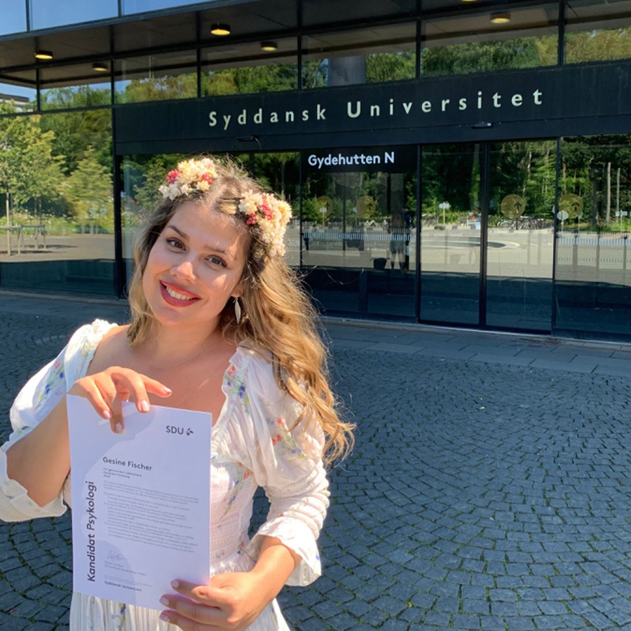 Kvinne med diplom utenfor et universitet. 
