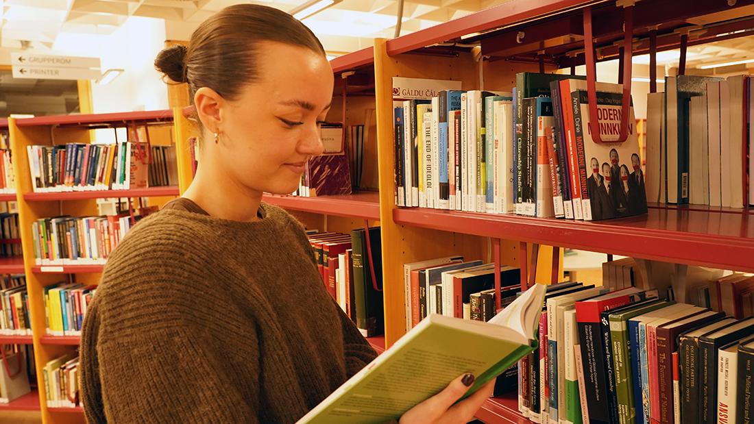 Jente som studerer på biblioteket. 