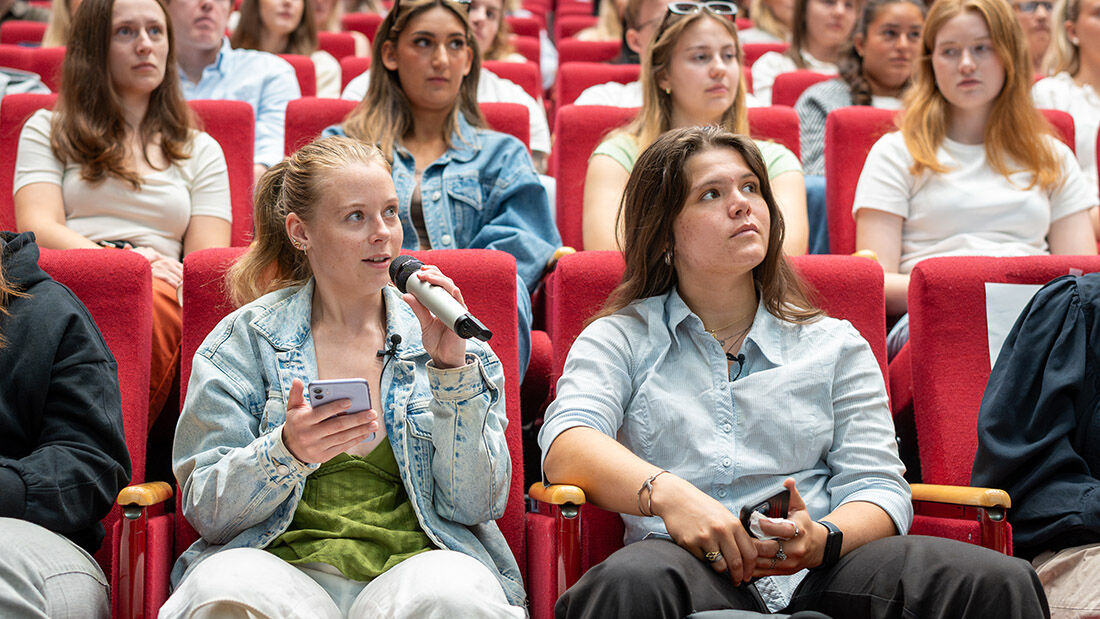 To kvinnelige studenter med en mikrofon. 