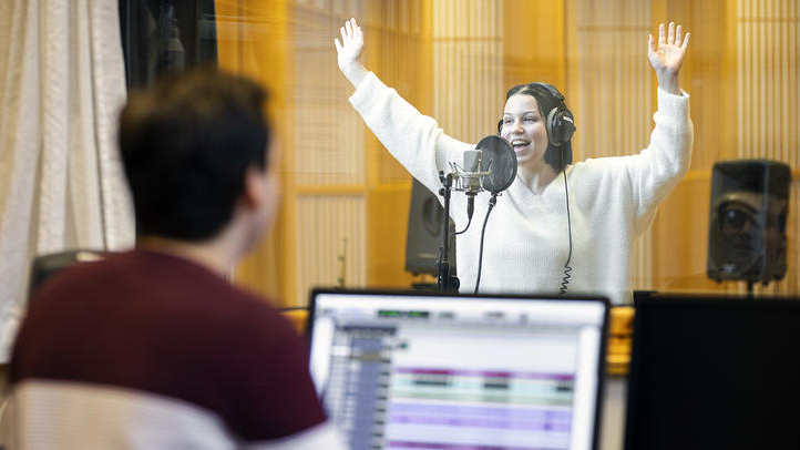 Kvinnelig musikkstudent som synger i studio. 
