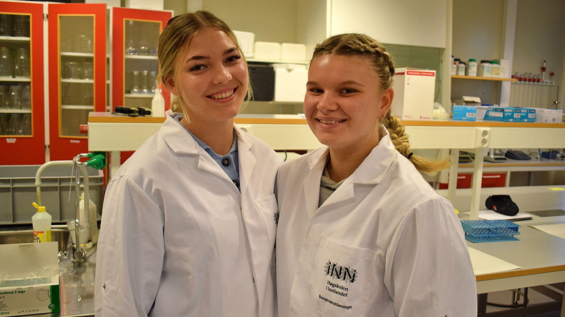 To smilende studenter i et laboratorium. 