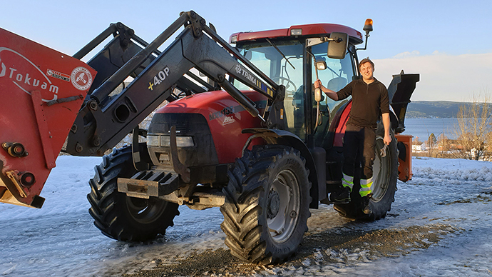 Mann hengende på siden av en traktor. 