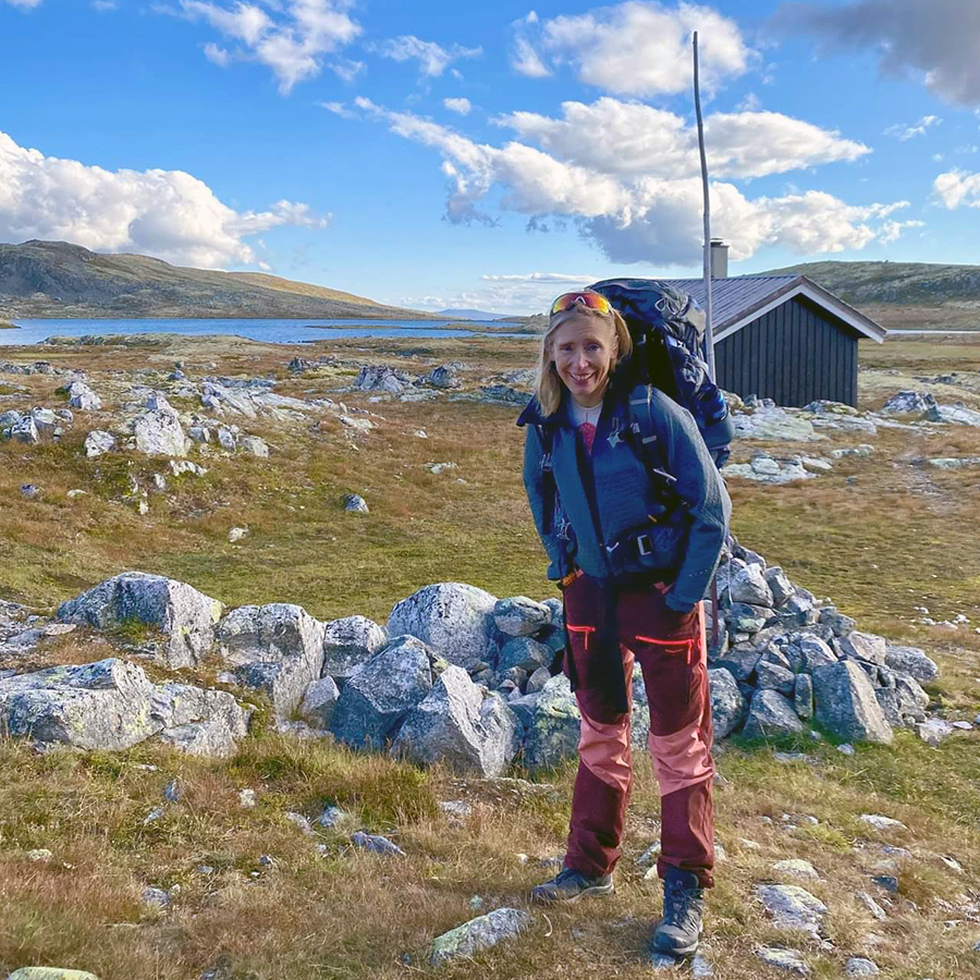 Kvinne på fjelltur i strålende solskinn. 