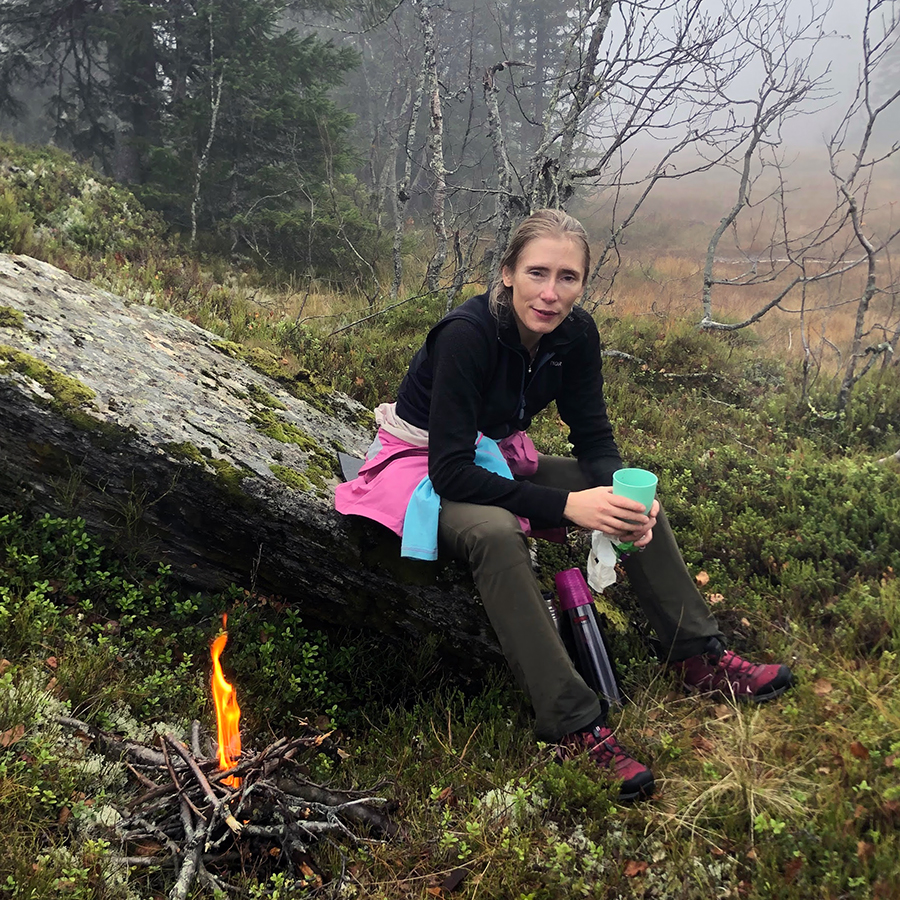 Kvinne som sitter ute i skogen. 