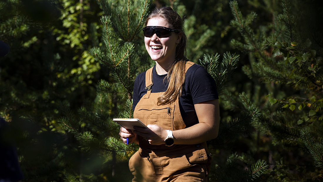En smilende student ute i skogen.