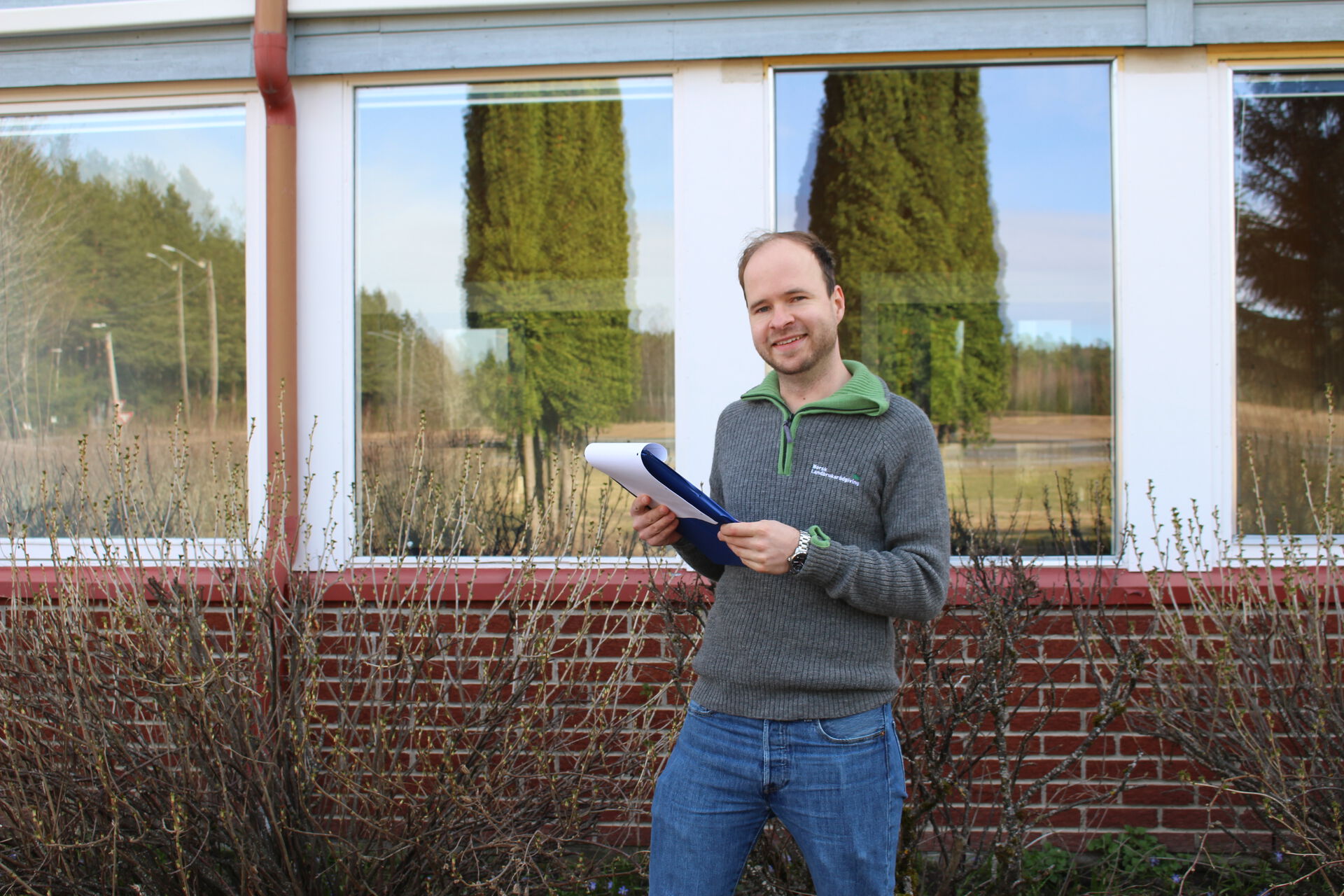 Michael står foran en bygning og holder papir i hånden.