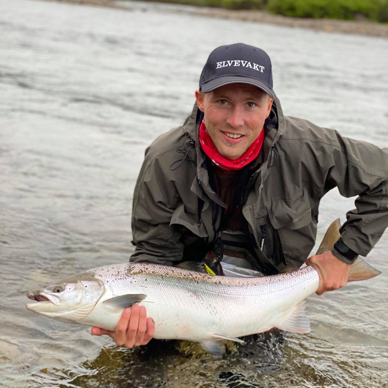 Student med en fisk som han har fikset i en lakseelv i Østerdalen. 
