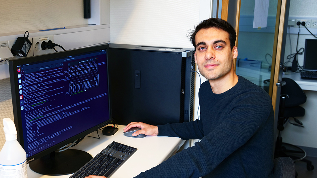 Mann kledd i mørk genser og bukse som jobber på en PC. 