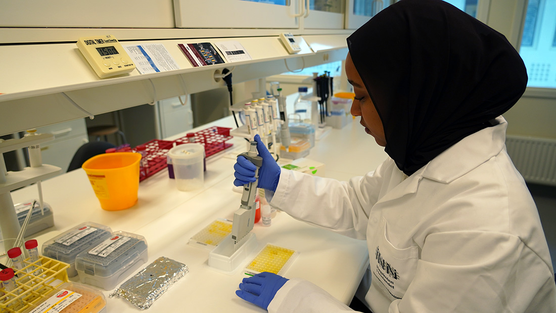 Student kledd i hvit som rydder utstyr på en lab. 