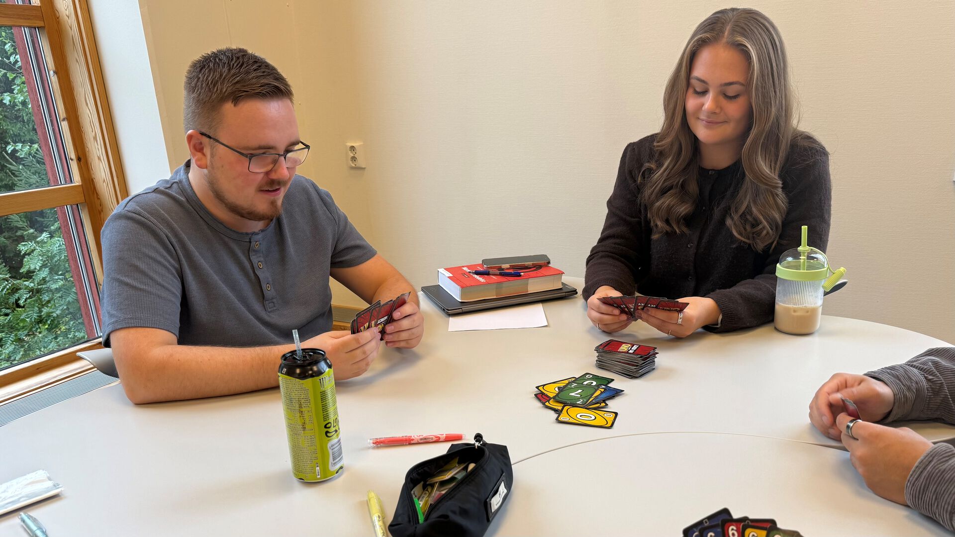 To studenter sitter i biblioteket på Rena og spiller Uno