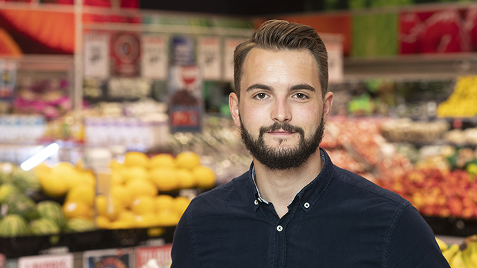 Mann foran en grønsaksdisk i en butik. 
