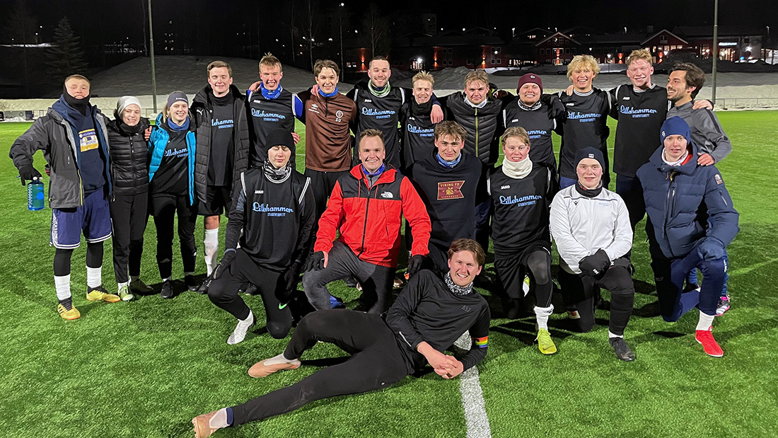 Gruppebilde av studenter kledd i mørke treningsklær på en fotballbane. 