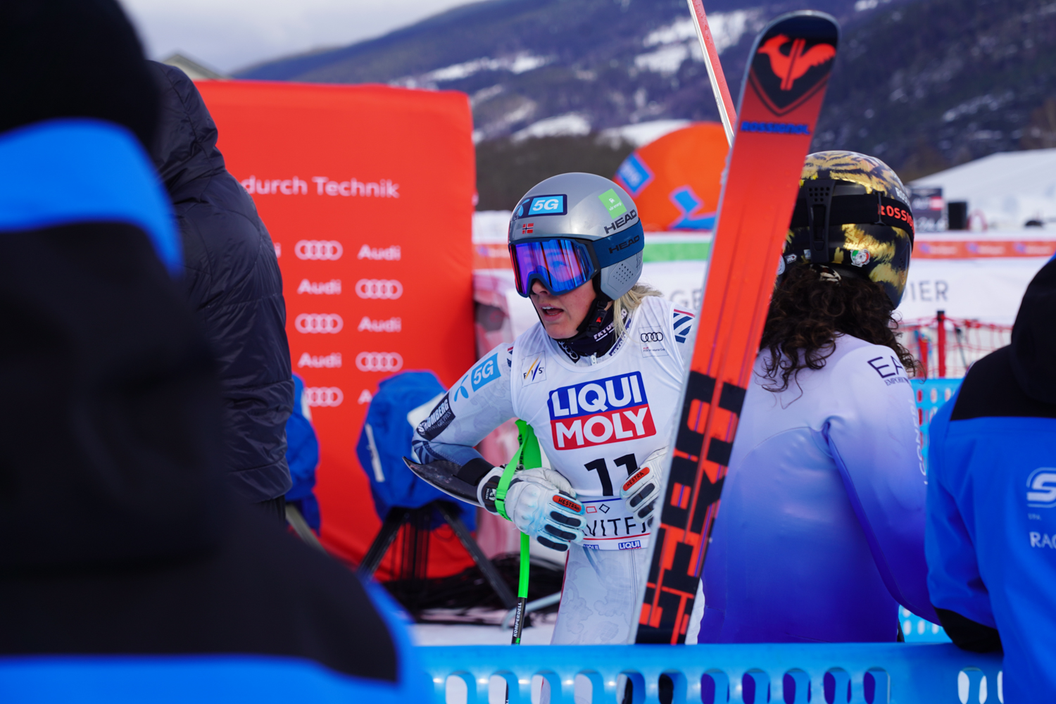 Kajsa Vickhoff Lie med hjelm og konkurransedrakt i utfor henger på stavene i målområdet i KVitfjell