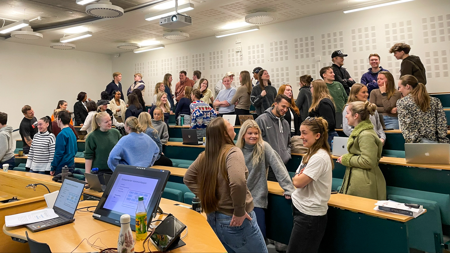 En hele klasse står i et auditorium og gjør oppgaver med hverandre