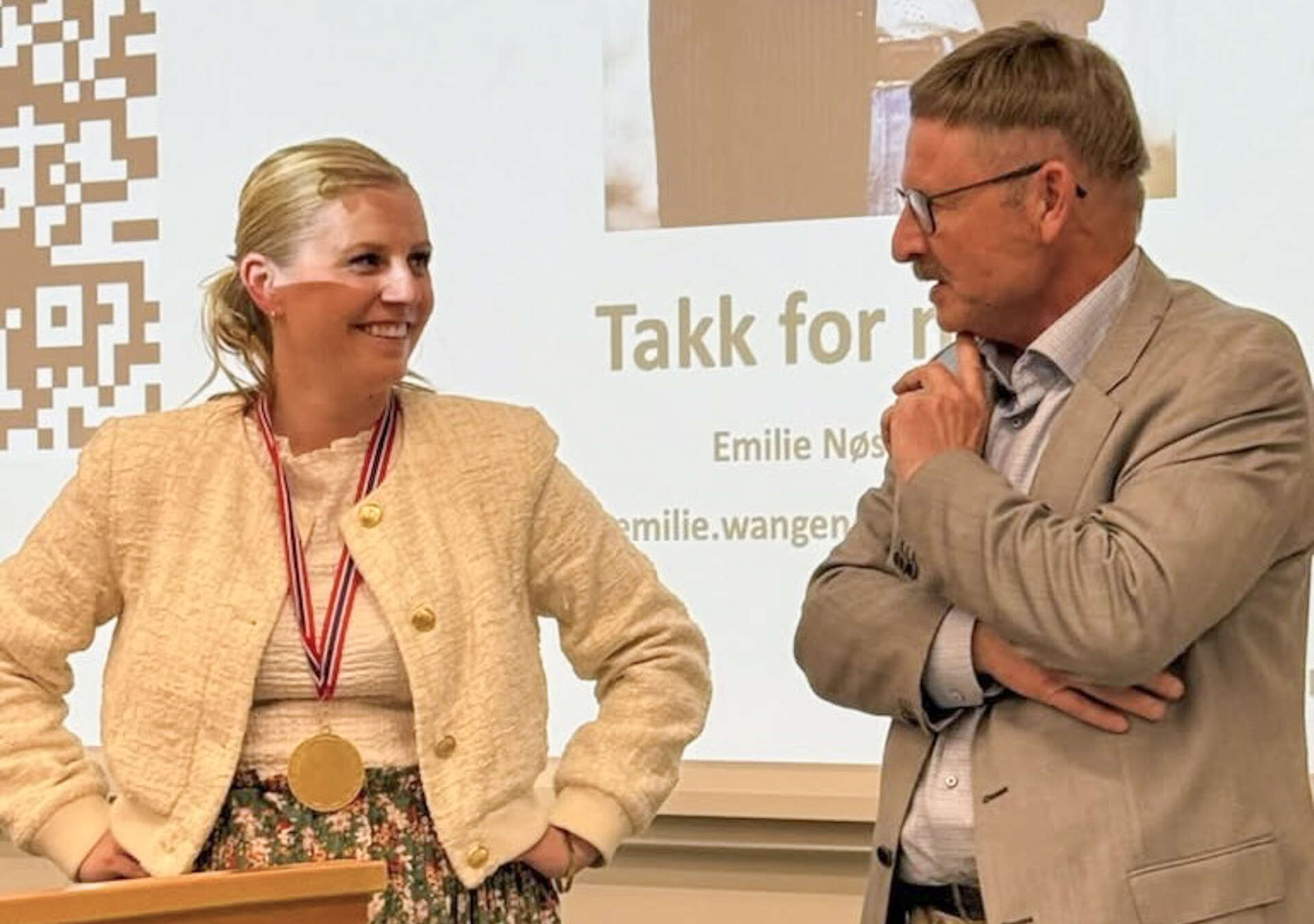 Dame og mann står foran et lerret i et auditorium