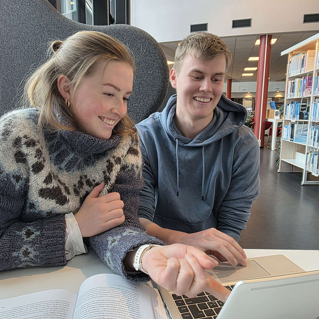 To smilende studenter som peker på en skjerm.