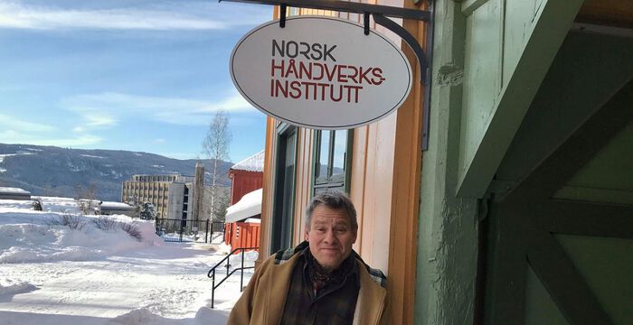 Eivind Falk utenfor et hus på Maihaugen. 