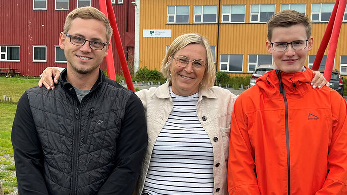 To lærere og en rektor utenfor en skolebygning. 