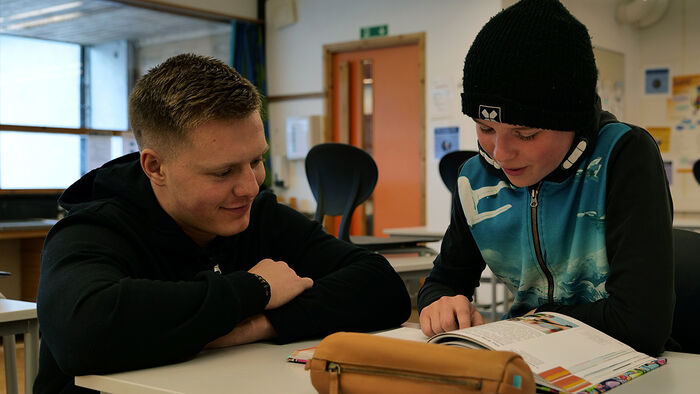 Mannlig lærerstudent i klasserom med elev.