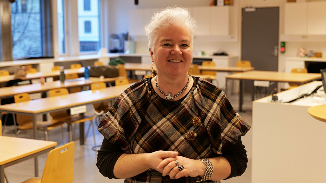 Kvinne i mørke klær i et klasserom. 