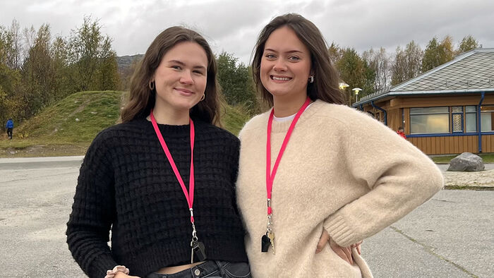 To kvinner som står utendørs foran en skolebygning. 