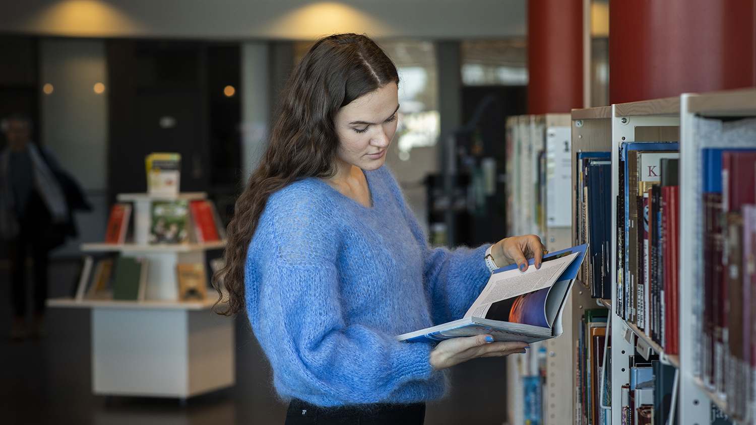 Portrettfoto av kvinnelig student som leser i en bok. 