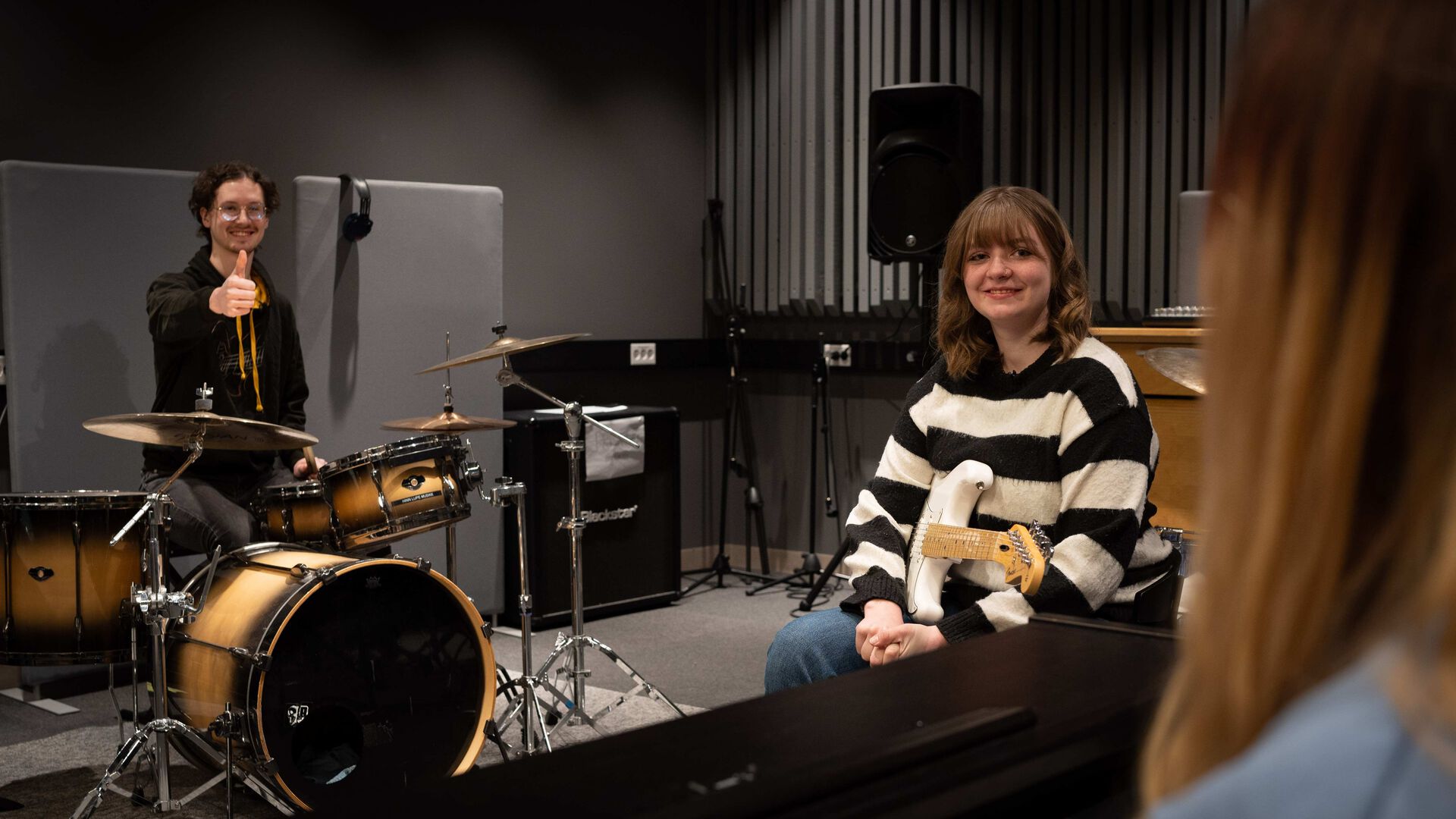 Top musikkstudenter på Hamar, en står vak trommene og en holder en gitar.