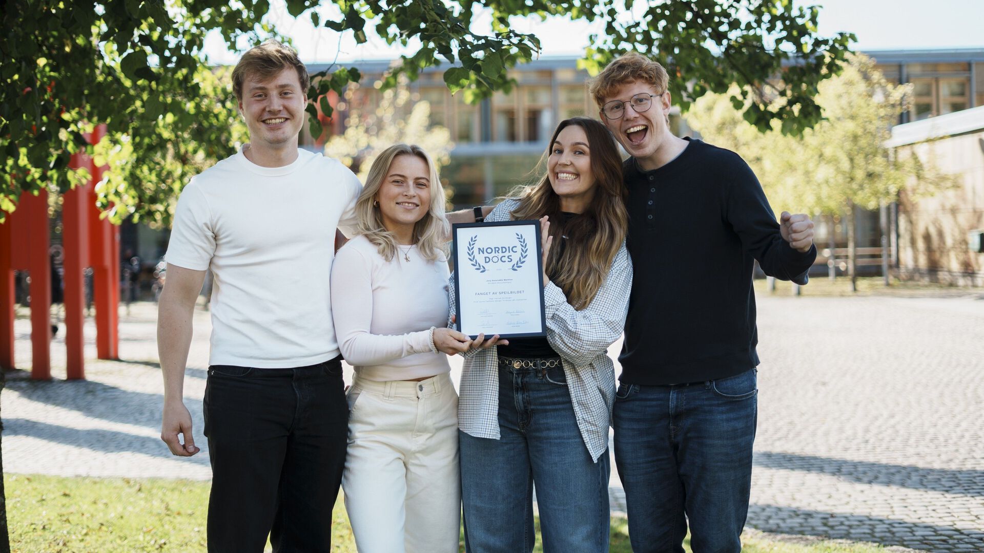 Fire glade studenter holder en innrammet diplom med overskrift Nordic Docs