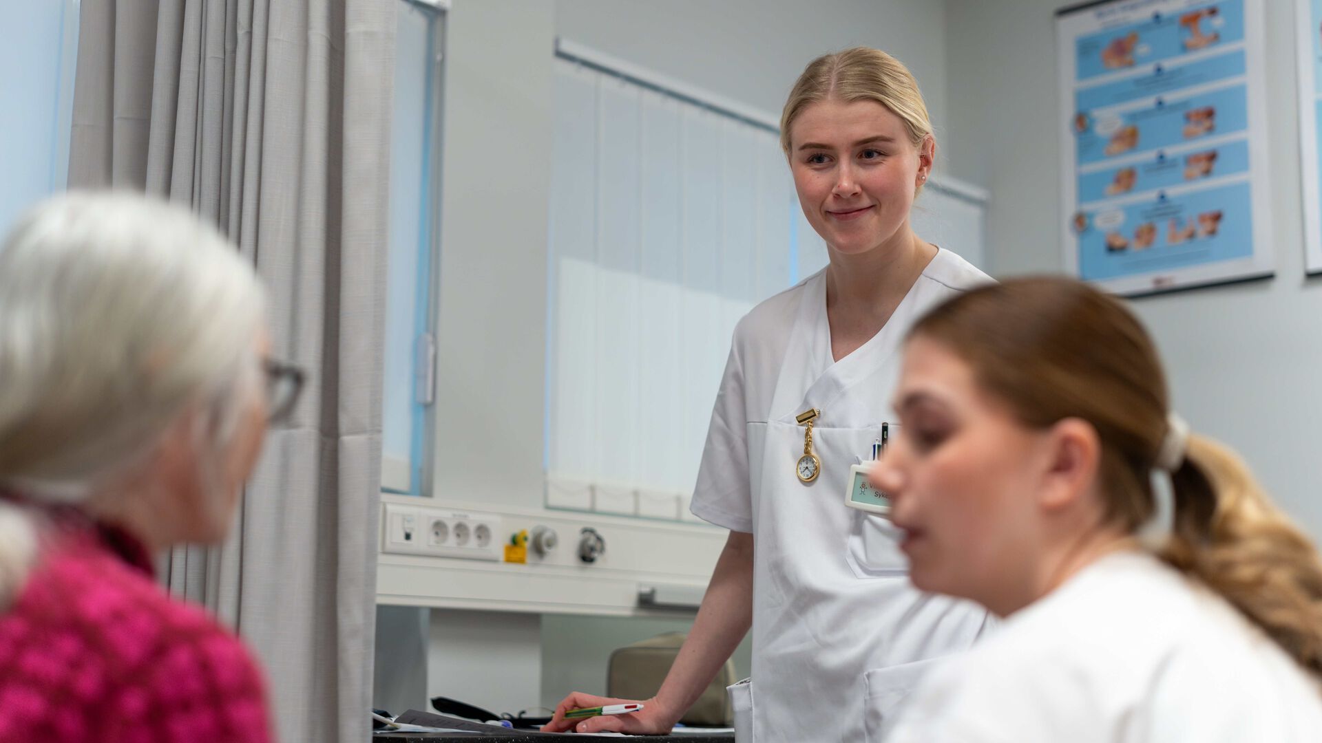 To sykepleiestudenter i samtale med en eldre kvinne.