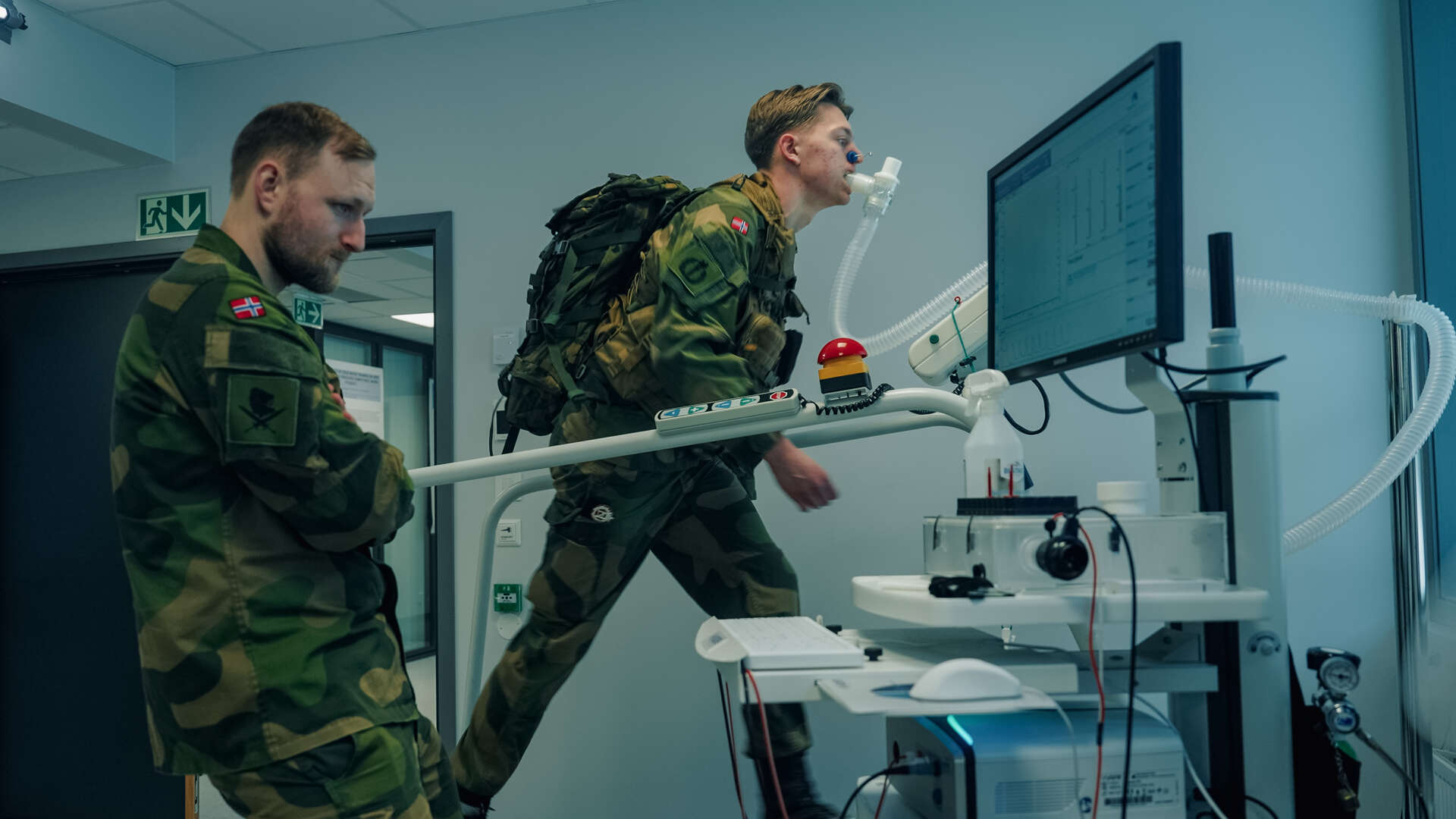 En soldat tester seg på VO2 max test på tredemølla på idrettslabben. Et befal står å følger med på skjermen