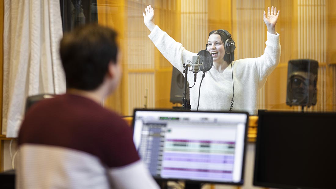 Bildet viser en kvinnelig student som synger i studio.