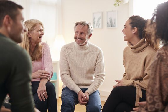 Voksne mennesker sitter i en gruppe og diskuterer