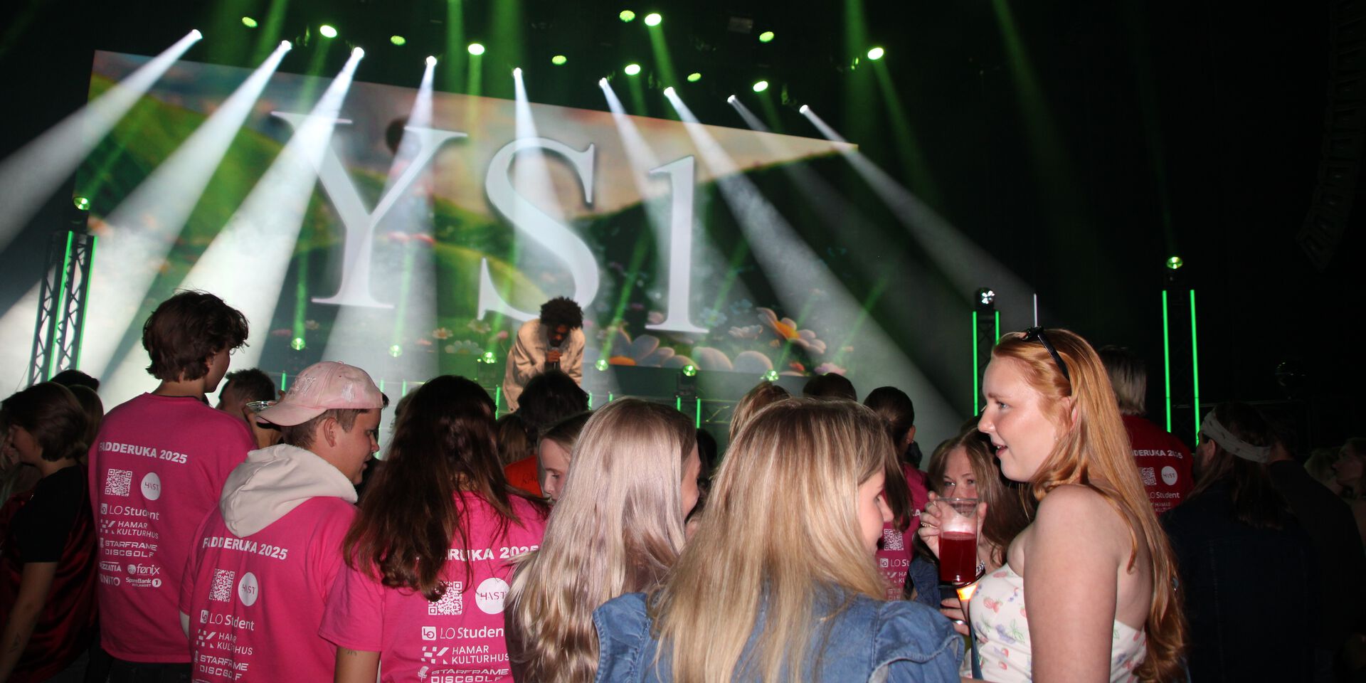 Studenter i publikum for konrert med YS1 på Hamar Kulturhus. Noen har fadder t-skjorter og andre har festklær.