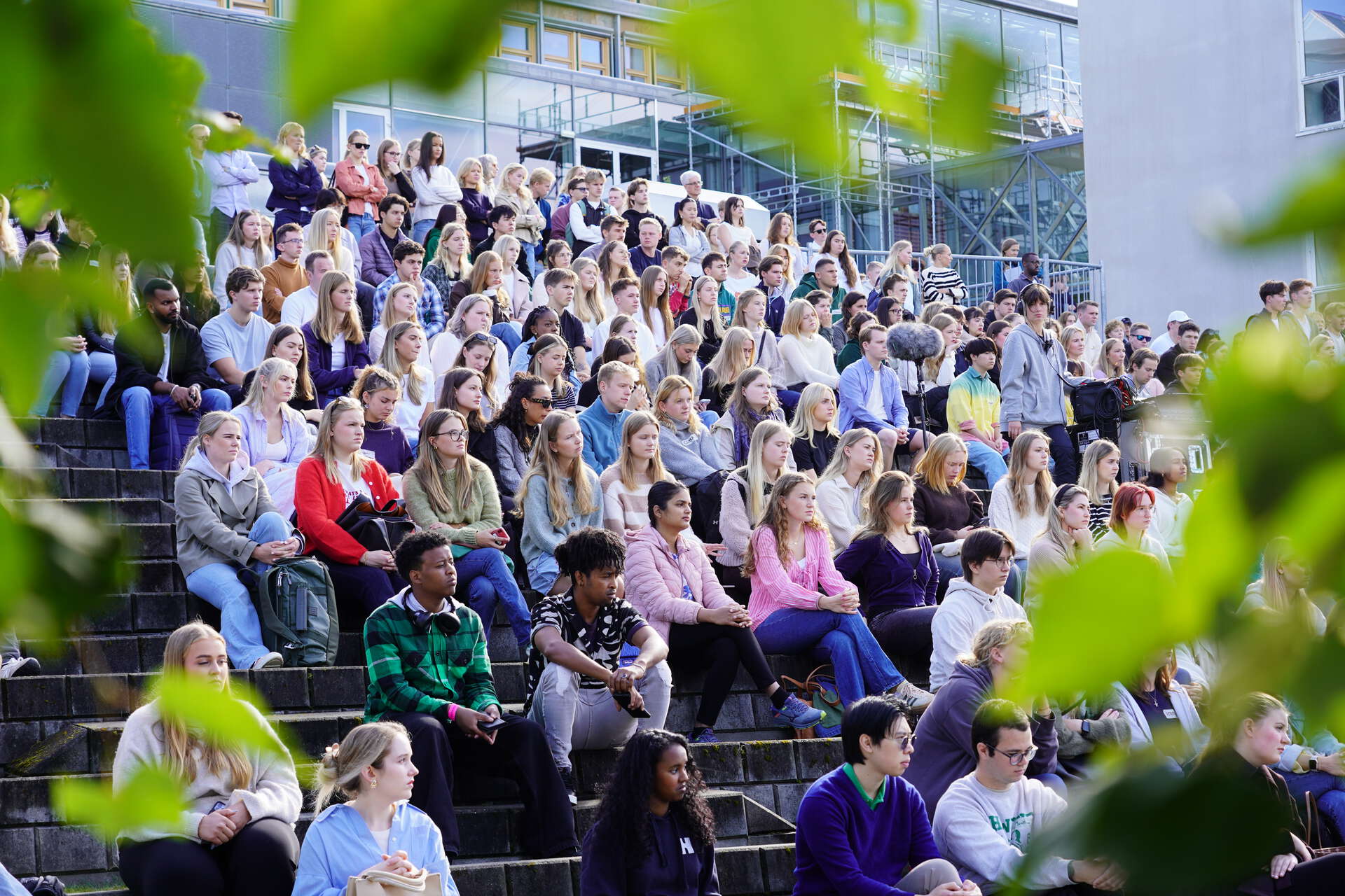 Bilde med studenter som sitter og følger med på åpningssermonien på campus Lillehammer. Blader ligger rundt som en slags ramme.